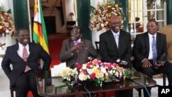 From left, Prime Minister Morgan Tsvangirai, President Robert Mugabe and other Zimbabwean officials address a press conference at the State House, Harare, Jan. 17, 2013.