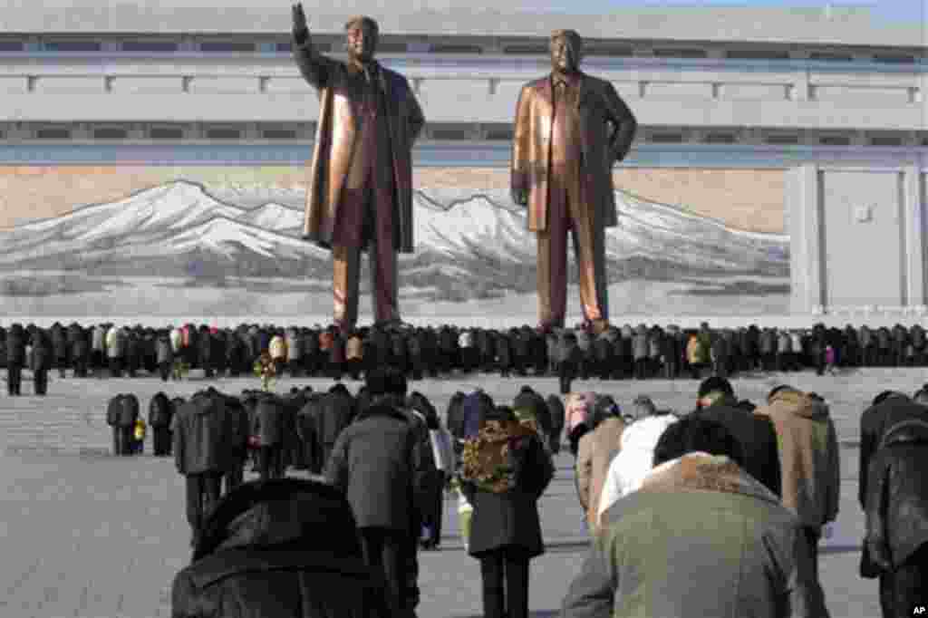 North Koreans bow before the statues of late leaders Kim Il Sung, left, and Kim Jong Il, right, at Mansu Hill in Pyongyang, North Korea, Monday, Dec. 17, 2012. At noon, North Koreans across the country stopped in their tracks to pay tribute to late North Korean leader Kim Jong Il in honor of the first anniversary of his death. (AP Photo/Ng Han Guan)