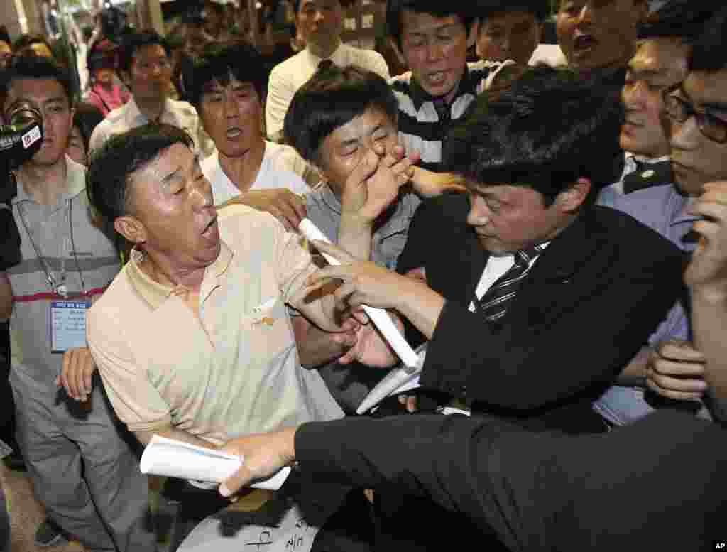 Family members of passengers aboard the sunken ferry Sewol struggle with a security officer, right, while attempting to attend a pretrial hearing for the ferry&#39;s crew members at Gwangju District Court in Gwangju, South Korea, June 10, 2014.