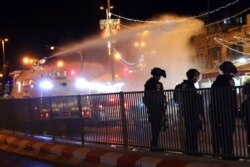 FILE - Israeli police use a water cannon to disperse Palestinian protesters from the area near the Damascus Gate to the Old City of Jerusalem after clashes at the Al-Aqsa Mosque compound, May 7, 2021.