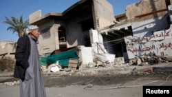 2013年12月15日一名男子站在巴格达汽车炸弹袭击现场附近(资料照片)