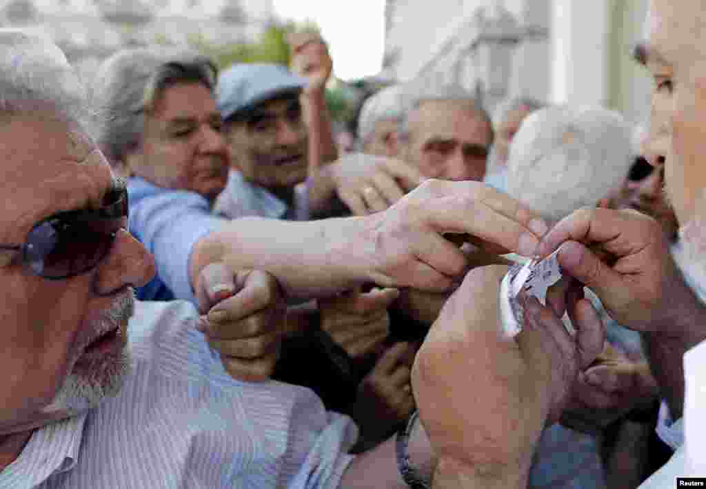 Pensioners are given priority tickets as they wait to receive part of their pensions at a National Bank branch in Athens, Greece, July 6, 2015.