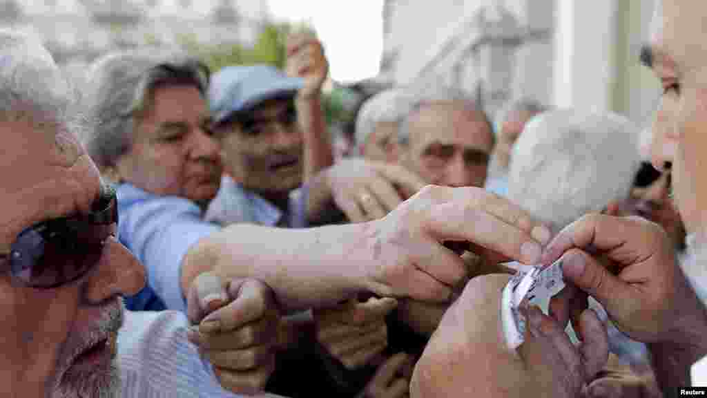 Des retraités recevant en priorité des tickets pour recevoir une partie de leurs pensions, devant la Banque nationale à Athènes, en Grèce