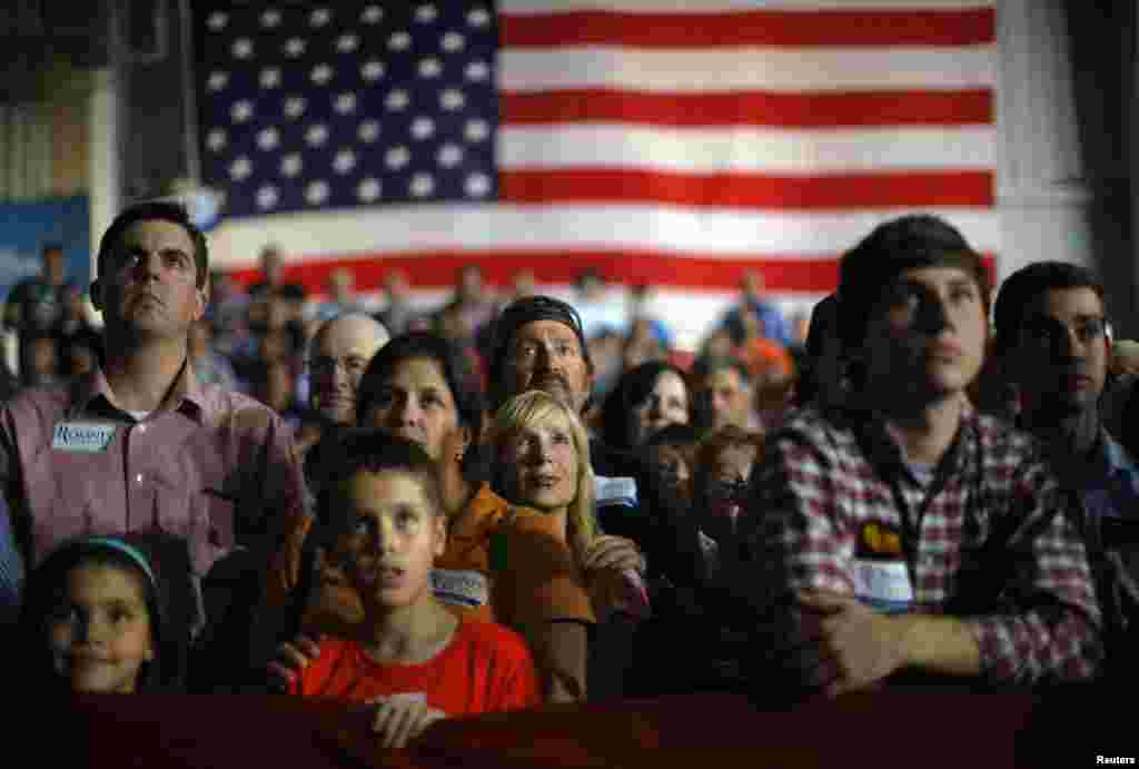 Audience members listen as Republican presidential nominee Mitt Romney speaks at a campaign rally in Cedar Rapids, Iowa, October 24, 2012. 