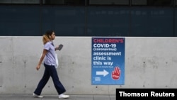 A person walks past a sign for a coronavirus disease assessment clinic in Sydney, Australia, Dec. 10, 2020. 
