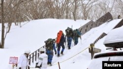 Sekouris kap monte nan mòn nan pou al ede etidyan ki bloke nan nèj kote moun kon al pratike ski nan vil Nasu, Tokyo, Japon, (Foto: Kyodo/via REUTERS. Lendi 27 mas, 2017.