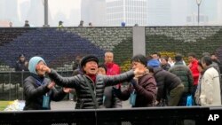 Chinese officials try to control a relative of a New Year's Eve stampede victim as she grieves at the site of the tragedy in Shanghai, China, Jan. 6, 2015.