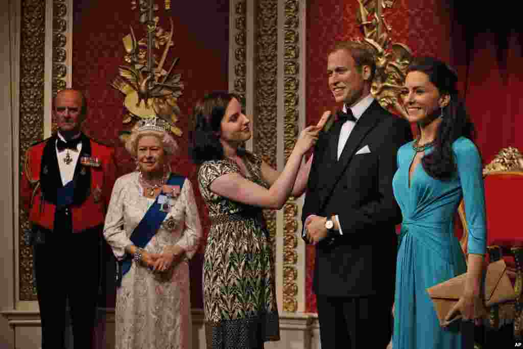 A Madame Tussauds employee prepares the wax figures of Britain&#39;s Prince William, left, and his wife Kate, right, the Duchess of Cambridge, in London. The wax figures of the royal couple were given a new look two years after they were introduced into the attraction.