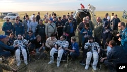 The International Space Station crew - U.S. astronaut Terry Virts (L), Italian astronaut Samantha Cristoforetti (R) and Russian cosmonaut Anton Shkaplerov (C) - rest after their landing in a remote area outside the town of Dzhezkazgan, Kazakhstan, June 11.