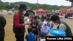 Relawan IBU Foundation membagikan masker untuk anak-anak di shelter terintegrasi Kementerian Sosial RI di Stadion Manakarra, Mamuju Sulawesi Barat, Minggu (31/1/2021). (Foto: VOA/Yoanes Litha)