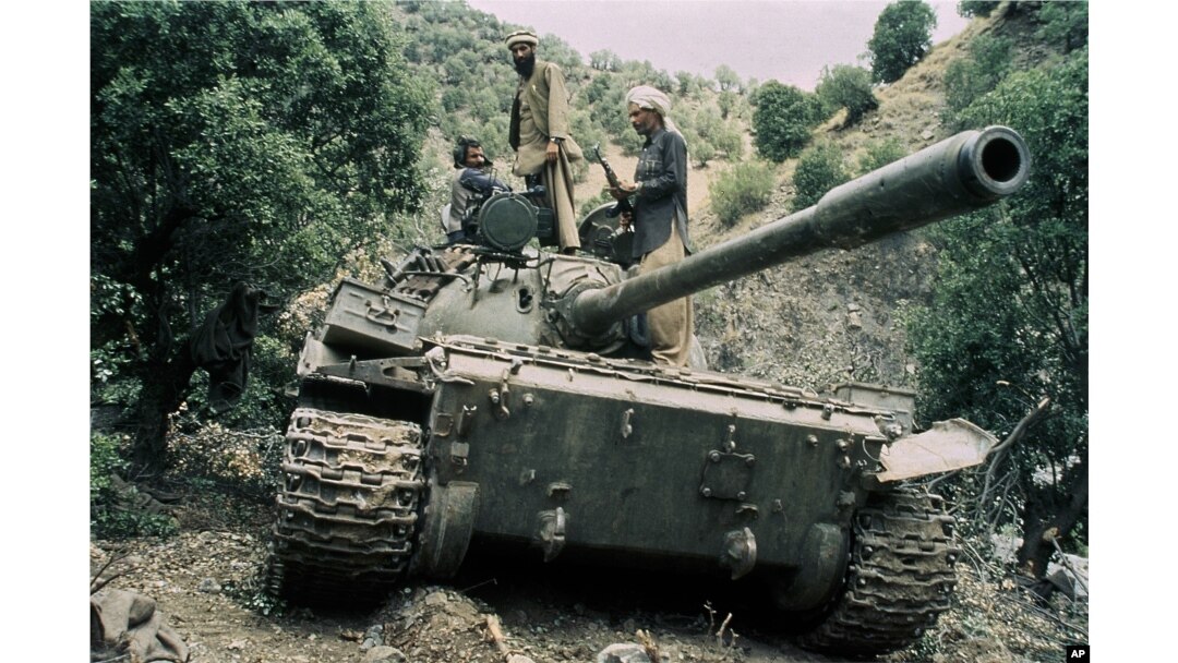 FILE - Mujahedeen guerrillas sit atop a captured Russian T-55 tank in 1987. The U.S. supported the anti-communists rebels against the Soviets.