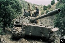 FILE - Mujahedeen guerrillas sit atop a captured Russian T-55 tank in 1987. The U.S. supported the anti-communist rebels against the Soviets.