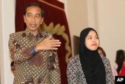 Indonesian president Joko Widodo, left, walks with Siti Aisyah, formerly accused of killing North Korean leader Kim Jong Un's estranged half brother, right, after a meeting at the presidential palace in Jakarta, Indonesia, March 12, 2019.