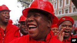 FILE - Julius Malema, center, leader of the Economic Freedom Fighters (EFF), arrives at Parliament wearing a hard hat and overall to show solidarity with coal mine workers, in Cape Town, South Africa, May 21, 2014.