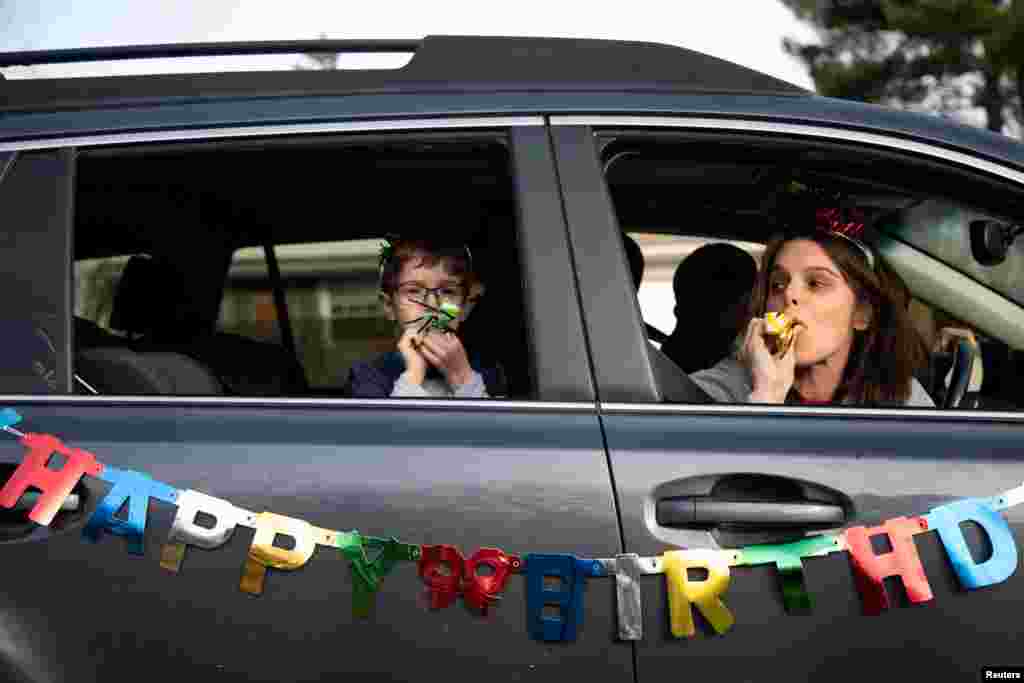 Dana Baer and her son Jacob Baer wish Avery Slutsky a happy sixth birthday from their car during a drive-by birthday celebration as they maintain social distance amid the coronavirus outbreak across the country in West Bloomfield Township, Michigan, March