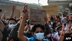 FILE - Protesters hold up the three finger salute and placards denouncing the move to shut down internet access during a demonstration against the military coup in Yangon, Feb. 7, 2021. 
