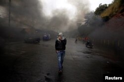 An opposition supporter walks amid smoke during clashes with police after the Organization of American States rejected a declaration of victory for Honduran President Juan Orlando Hernandez in a sharply disputed election, in Tegucigalpa, Dec. 18, 2017.