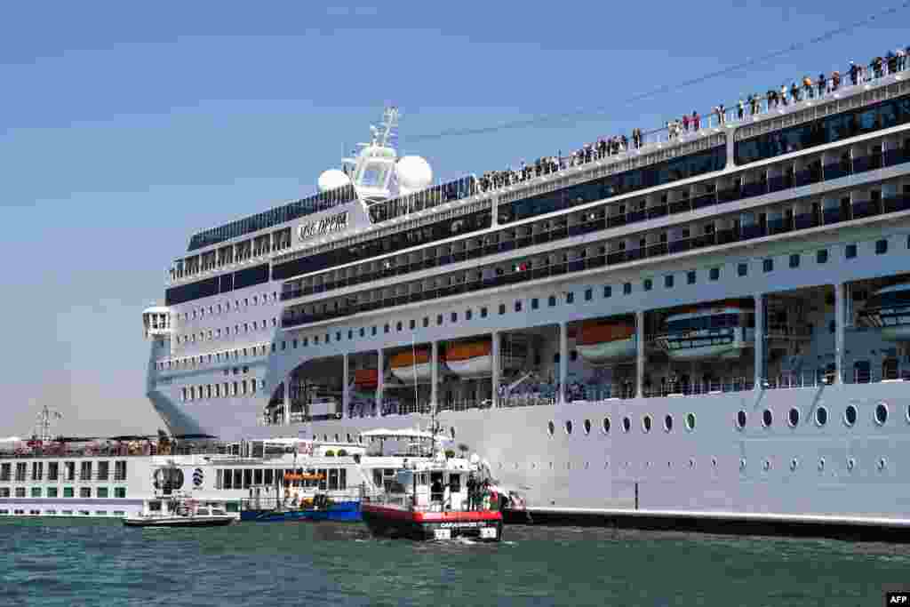 Rescuing boats of the Carabinieri Police (Front) and the port&#39;s fire rescue service (2ndL) assist the damaged River Countess tourist boat (Rear L) after it was hit by the MSC Opera cruise ship (R) that lost control as it was coming in to dock in Venice, Italy. Tourists on land could be seen running away as the MSC Opera scraped along the dockside, its engine blaring, before knocking into the River Countess tourist boat.