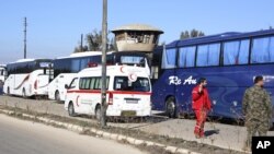 Syrian civilians in buses leave the Waer neighborhood, in the city of Homs, Syria, as part of a deal with local government forces in which dozens of of insurgents are also being allowed safe passage to areas in the country's north, Dec. 9, 2015.
