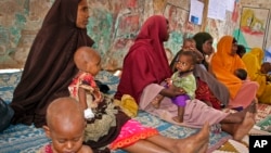 FILE - In this photo taken March 25, 2017, Somali women and their malnourished children attend a health center in Baidoa, Somalia. 