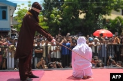 Seorang petugas agama mencambuk seorang pemuda Aceh di atas panggung sebagai hukuman karena berkencan di luar nikah, yang bertentangan dengan Syariah, atau hukum Islam, di luar sebuah masjid di Banda Aceh, 1 Agustus 2016. (Foto: AFP)