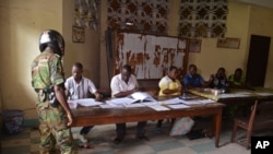 Un soldat Congo ( l), dans un bureau de vote , à Brazzaville , au Congo . Le président de la République sortant a gouverné le pays d'Afrique centrale depuis plus de 30 ans , devrait faire une croisière à une réélection dimanche,cinq mois après un référendum constitutionnel supprimé la limitation du mandat et l'âge qui aurait barré l'âge a 72 de M. Sassou Nguesso. (AP Photo / John Bompengo )