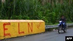 FILE - A motorcycle passes by a sign that reads "ELN" that refers to the National Liberation Army guerrilla group in Corinto, Valle del Cauca province, Colombia, June 6, 2024. The ELN announced a unilateral truce on Dec. 22, 2024, to last until Jan. 3, 2025.