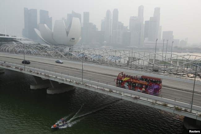 Sebuah bus wisata melewati kawasan pusat bisnis yang diselimuti kabut di Singapura pada 29 September 2015. (Foto: Reuters)