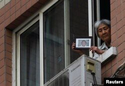 Zhang Xianling, whose son Wang Nan was killed by soldiers at the Tiananmen Square in 1989, holds his picture after journalists were turned away, at the window of her home in Beijing, April 24, 2014.