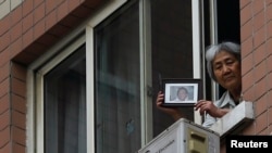 资料照：“天安门母亲群体”其中代表人物张先玲在住宅窗口展示八九六四在天安门被军队杀死的儿子的照片。