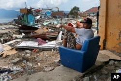 A man sits on a chair in the shell of a house heavily damaged by the tsunami in Wani village on the outskirts of Palu, Central Sulawesi, Indonesia, Oct. 4, 2018.