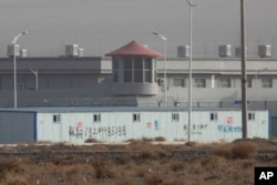FILE - In this Monday, Dec. 3, 2018, file photo, a guard tower and barbed wire fences are seen around a facility in the Kunshan Industrial Park in Artux in western China's Xinjiang region.