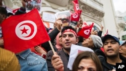 A Tunisian demonstrator waves a Tunisian flag during a rally in support of Tunisian President Kais Saied in Tunis, Tunisia, Sunday, May 8, 2022.