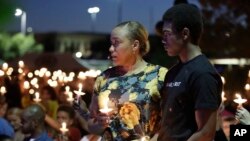 Veronica Hartfield, wife of Las Vegas police officer Charleston Hartfield, and son Ayzayah Hartfield stand during a candlelight memorial for the officer, Oct. 5, 2017, in Las Vegas.