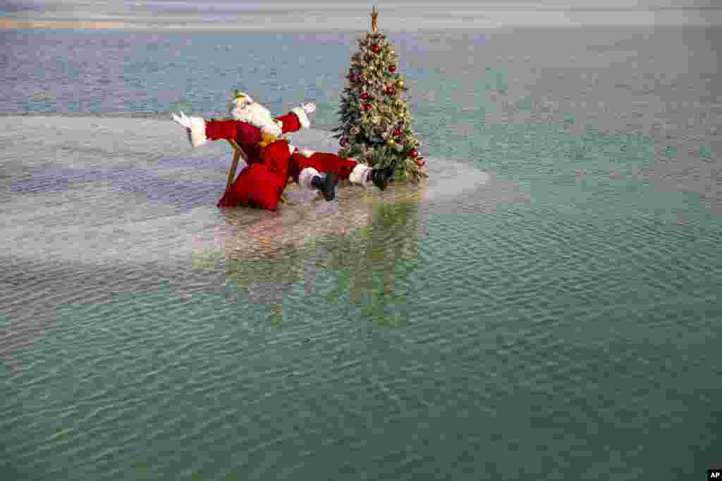 Issa Kassissieh dressed as Santa Claus sits next to a Christmas tree on a salt formation during filming for a Christmas greeting video from the Holy Land in the Dead Sea near Ein Bokeq, Israel.