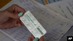 FILE - In this Sept. 2, 2022, photo, a woman distributes packs of iodine tablets to residents at a local school in case of a radiation leak in Zaporizhzhia, Ukraine.