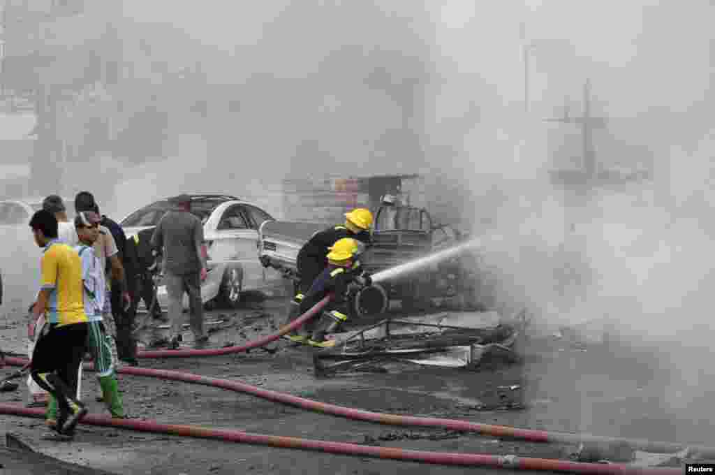 Firefighters try to put out the flames after two car bombs went off in Nassiriya city, Iraq, July 14, 2013.