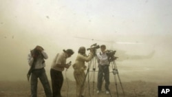 Journalists take cover as the helicopter carrying the late U.S. special envoy Richard Holbrooke lands in Mardan district, about 120 km northwest of Pakistan's capital Islamabad. (FILE)