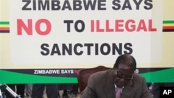 FILE: Zimbabwean President Robert Mugabe signs a petition against Western economic sanctions targeting his supporters, in Harare, Wednesday, March, 2, 2011.