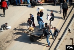 Men struggle to carry products up and down the steep slopes of the broken bridge, but they say business is still steadily improving, in Mosul, Iraq, Jan. 19, 2017. (H. Murdock/VOA)