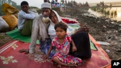 Rohingya man Nur Ahmad, 70, his wife Lalu Bibi and their grand daughter Ashuka Bibi, 5, who crossed over to Bangladesh the previous day, wait for permission to go to the refugee camps after spending the night in the rice fields near Palong Khali, Bangladesh, Nov. 2 2017. It took them nine days to reach the border since they left their family home at Buthi Dawng district. 