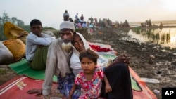 Warga Rohingya Nur Ahmad (70), istrinya Lalu Bibi dan cucu mereka Ashuka Bibi (5) yang melarikan diri ke Bangladesh menunggu izin untuk ditampung di penampungan pengungsi setelah menghabiskan waktu mereka di area persawahan dekat Palong Khali, Bangladesh, 2 November 2017. (Foto: dok). 
