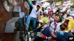 Anti-government protesters break the police sign outside police headquarters during a rally in Bangkok, Thailand, Jan. 22, 2014. 