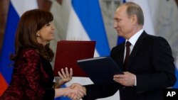 Russian President Vladimir Putin and Argentina's President Cristina Fernandez exchange documents at a signing ceremony in the Kremlin in Moscow, April 23, 2015.
