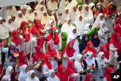 FILE - Members from UMNO, in red, and members of PAS wave their parties' flags during an event announcing an alliance between the two in Kuala Lumpur, Malaysia, Sept. 14, 2019.