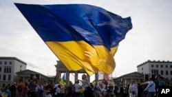 FILE - A woman waves a huge Ukrainian flag during rally to mark the 32nd anniversary of Ukraine's independence and to protest against the Russian war on Ukraine, in Berlin, Germany, Thursday, Aug. 24, 2023.