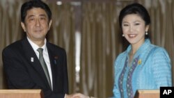 Japanese Prime Minister Shinzo Abe, left, poses with his Thai counterpart Yingluck Shinawatra for photographers at the end of a news conference at the Government House in Bangkok, Thailand, January 17, 2013.