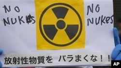 A protester in protective mask holds a placard during an anti nuclear rally in Tokyo, Sunday, March 27, 2011