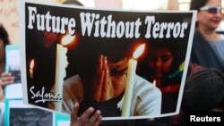 A boy holds a poster during a civil society protest rally against terrorism in Lahore, January 16, 2015.