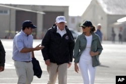 FILE - President Donald Trump and first lady Melania Trump walk with with Puerto Rico's Gov. Ricardo Rossello at the Luis Muniz Air National Guard Base before leaving the island, in San Juan, Puerto Rico, Oct. 3, 2017.